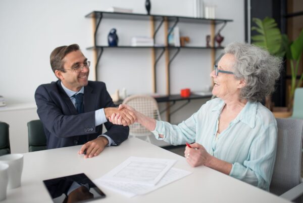 Comercial y cliente estrechando la mano tras aplicar venta consultiva B2B en una reunión de negocio
